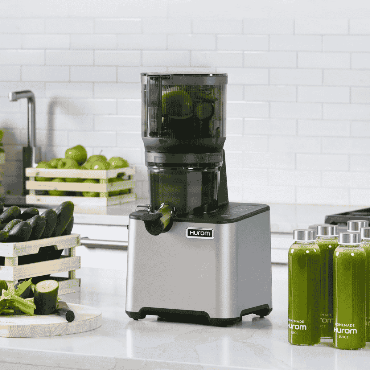 Hurom CP504 slow juicer on a kitchen counter with green juice bottles and fresh vegetables