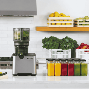 hurom CP505 slow juicer on a kitchen counter with colourful fresh juice bottles and fruits